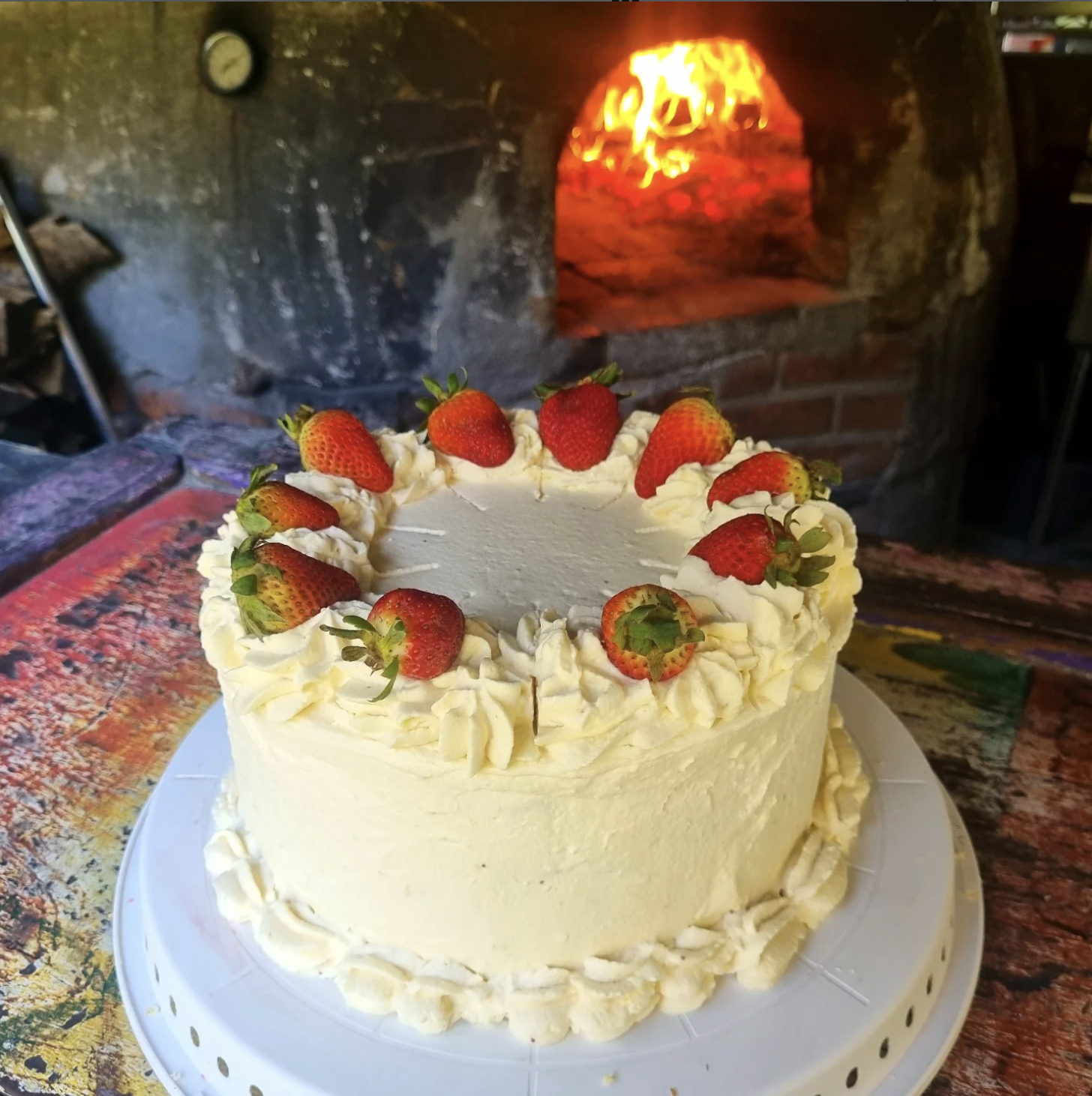 Pastel de fresas frente al horno de leña encendido