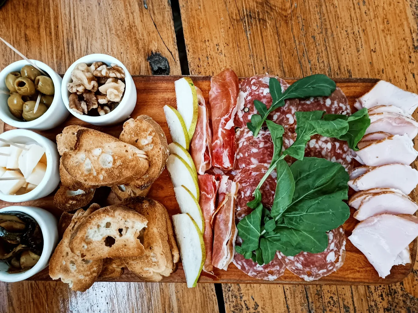 Tabla de jamones y quesos con embutidos, peras y pan tostado